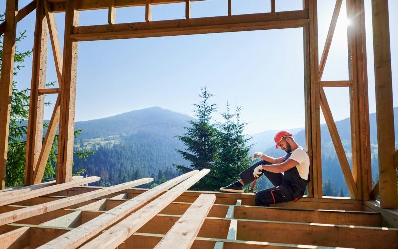 Carpenter constructing wooden frame house.