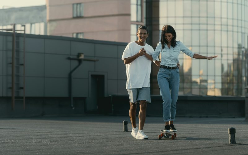 handsome-young-man-helping-his-girlfriend-to-ride-skateboard.jpg